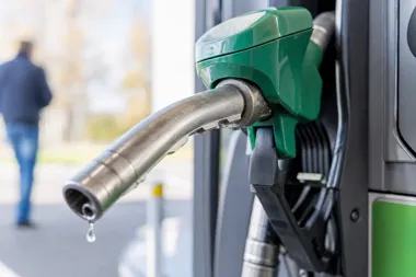 Zielony pistolet do tankowania paliwa na stacji benzynowej, z kroplą na końcówce dyszy.